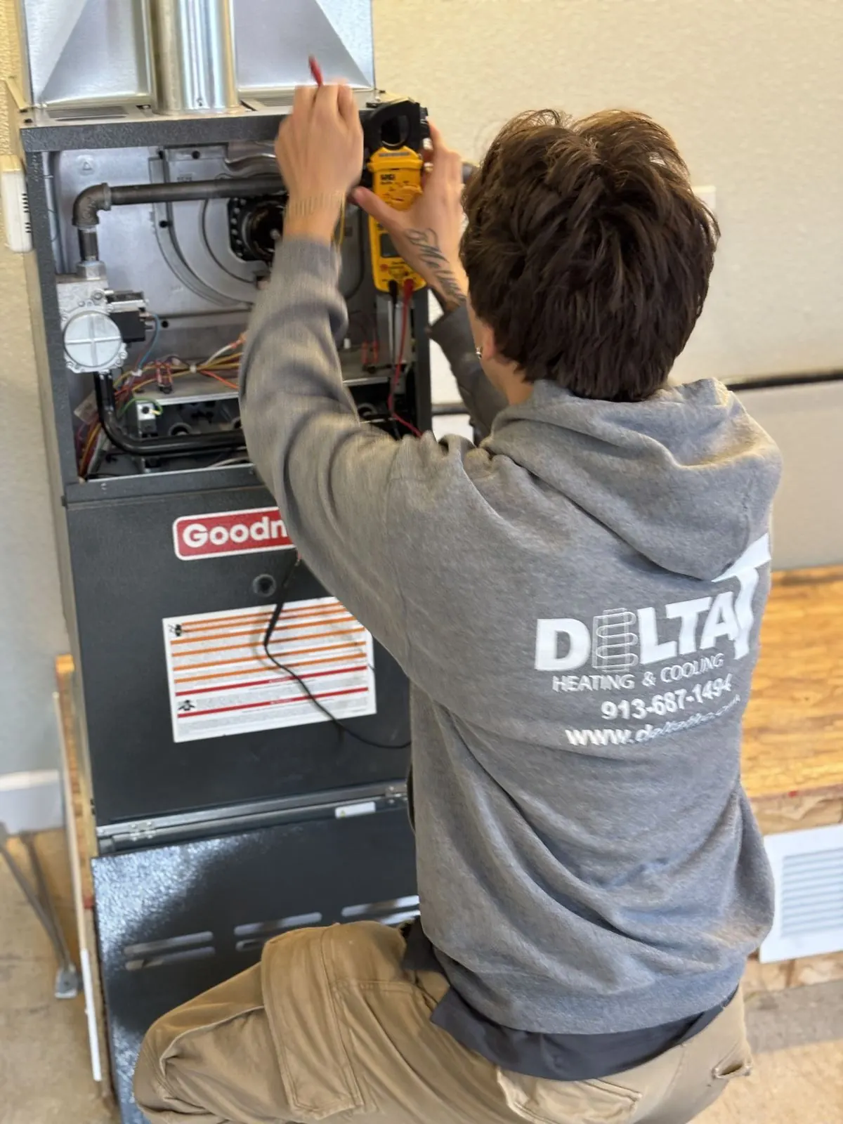 Delta T technician using a multimeter on a hot-day AC service call.